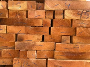 Placas de madeira recém-cortadas empilhadas de forma compacta, com números e linhas azuis visíveis nas extremidades para identificação ou medição.