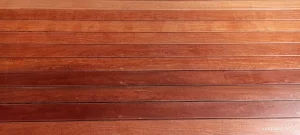 Superfície de madeira composta por tábuas horizontais em tom avermelhado, veios naturais visíveis, acabamento polido